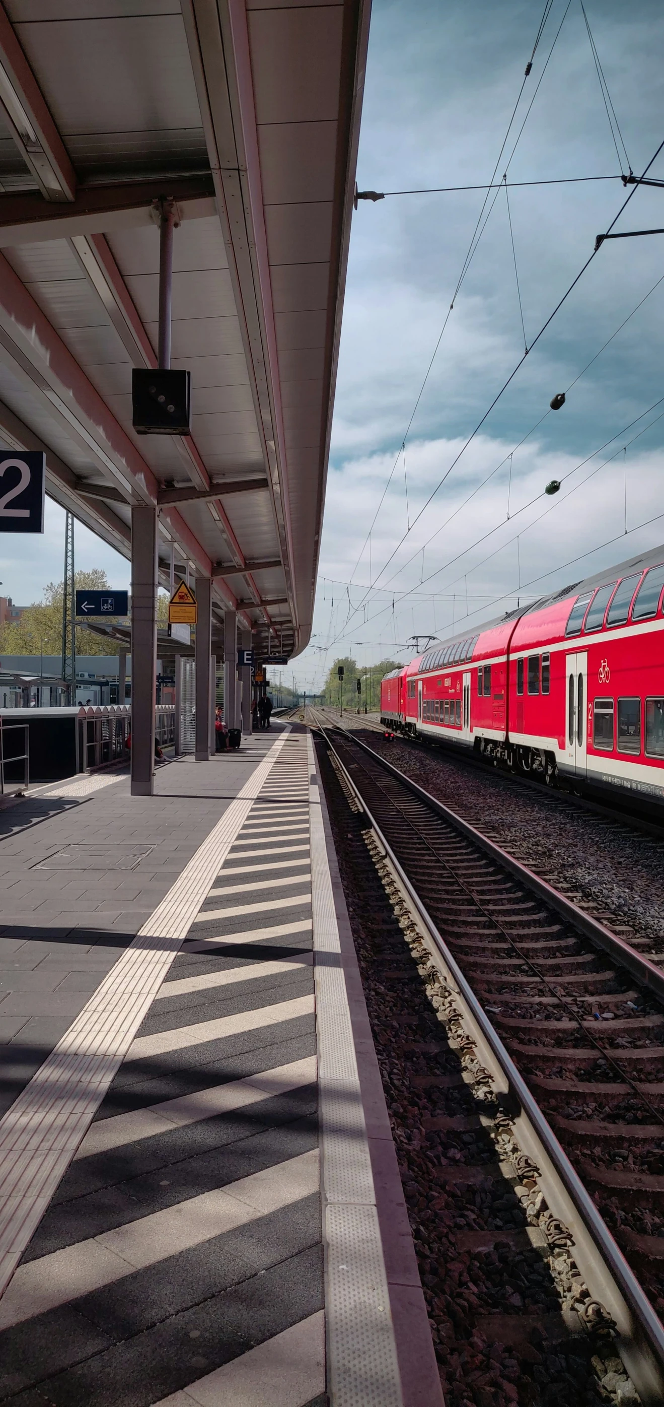 a red train sitting at the station on railroad tracks