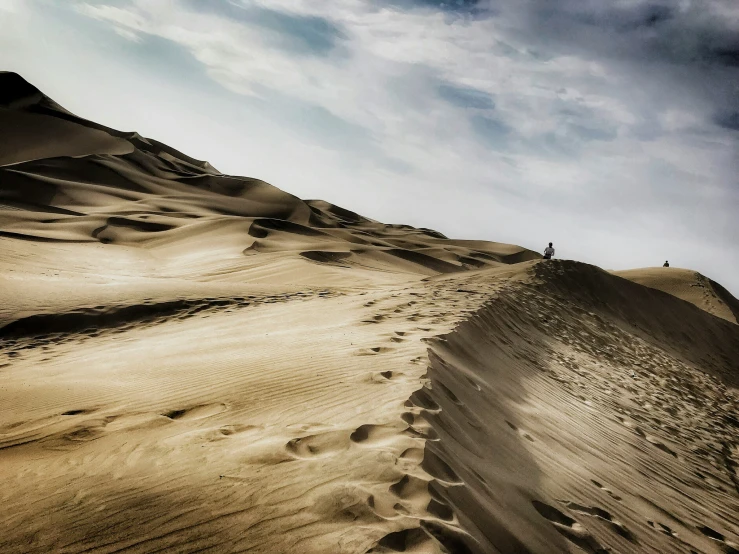 the lone person stands on top of a sand dune