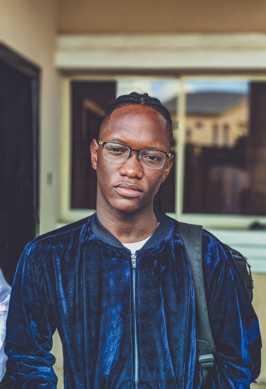 a black man is wearing glasses and standing in front of a house