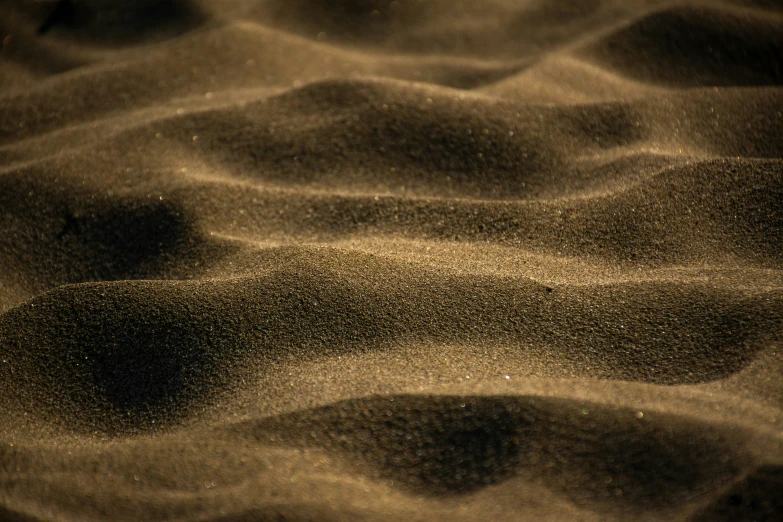 a sandy beach covered in sand with sand and grass underneath