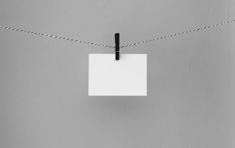 an electrical wire and a rectangle piece of paper hanging from wires