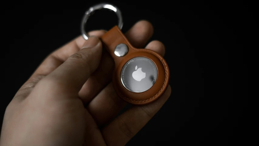 a man is holding an apple key fob in his hand