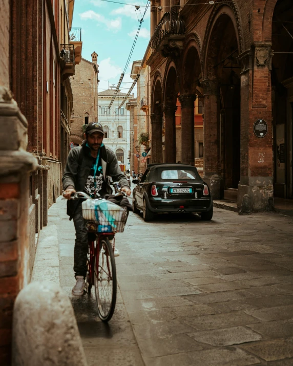 a man rides a bike past parked cars on the side of a street