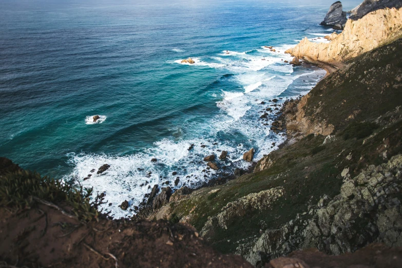 a cliff by the ocean with several people surfing