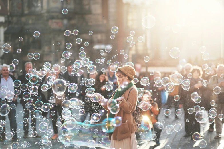 a girl is standing on the sidewalk and blowing bubbles