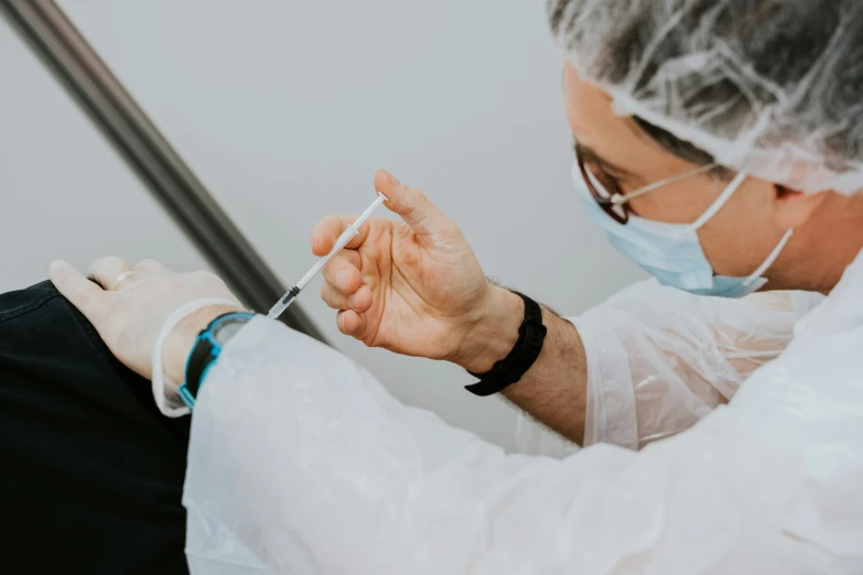 an older man in white surgical garb is placing soing on his hand