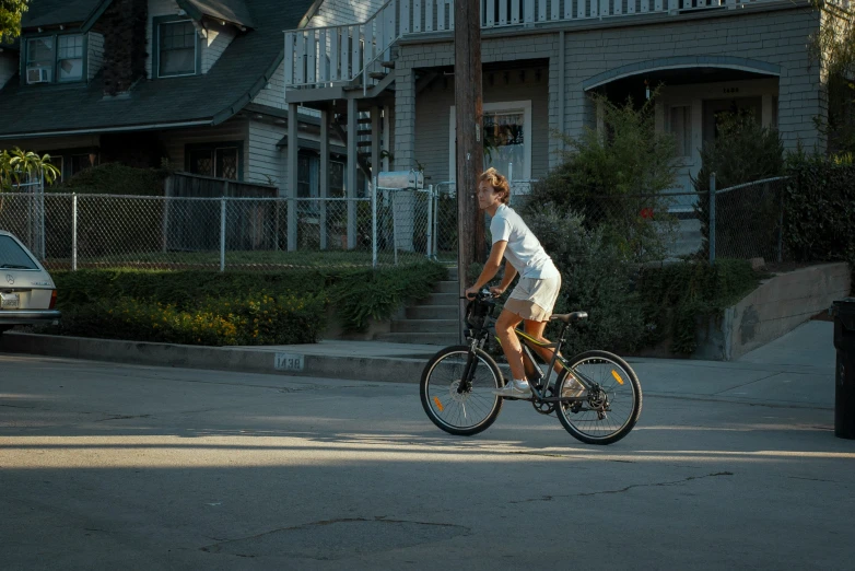 woman on a bicycle riding along the road in front of a house