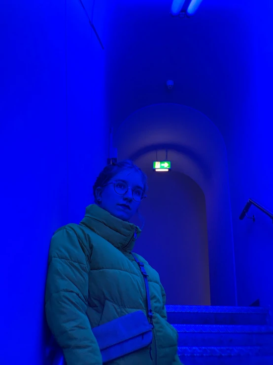 a woman with glasses standing near some stairs