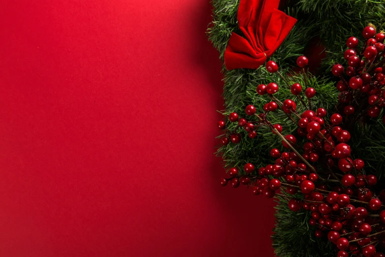 a red christmas wreath is tied to a wall