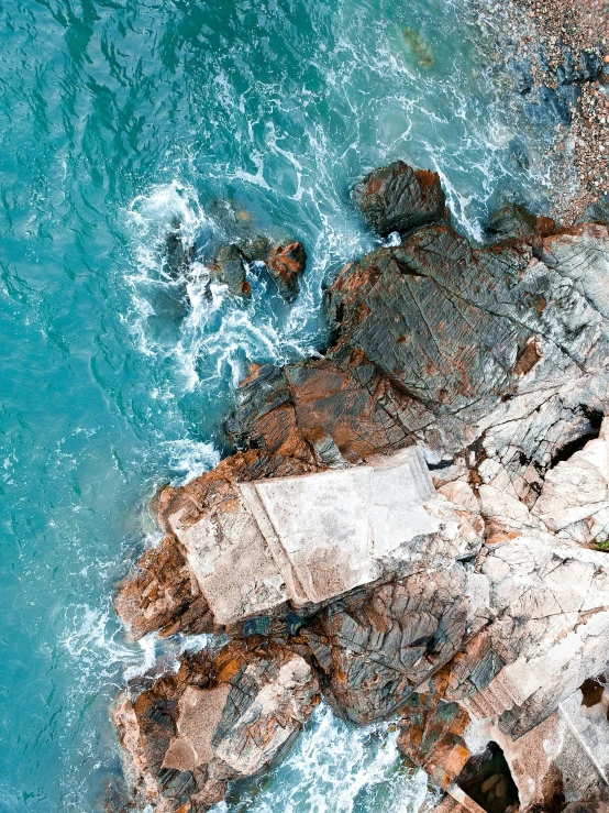 this po shows the view from above of two people standing on rocks near the ocean
