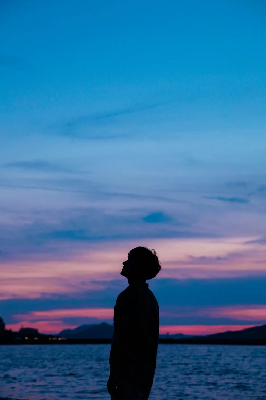 the man is standing by the lake at sunset