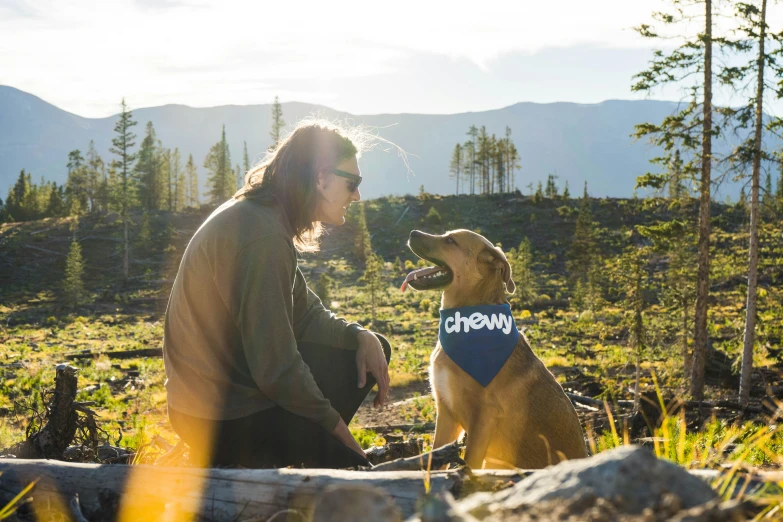 a man sitting next to his dog in the wilderness