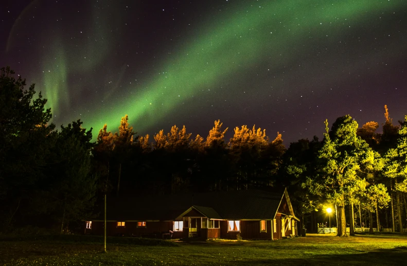 a house surrounded by green trees and an aurora light