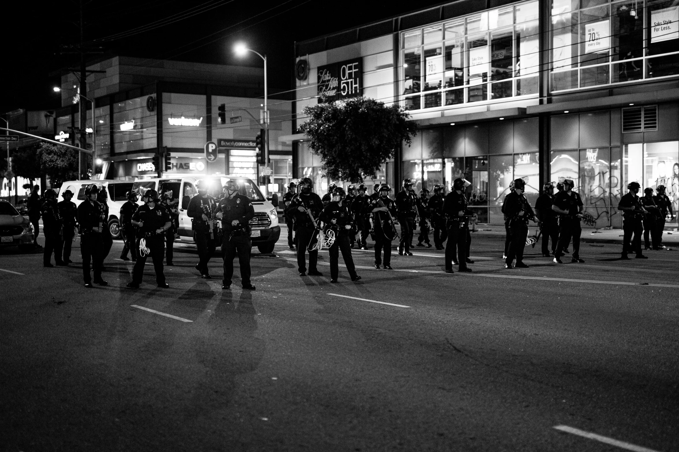 black and white image of police walking down street at night