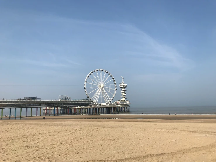 the ferris wheel on the beach is under a blue sky