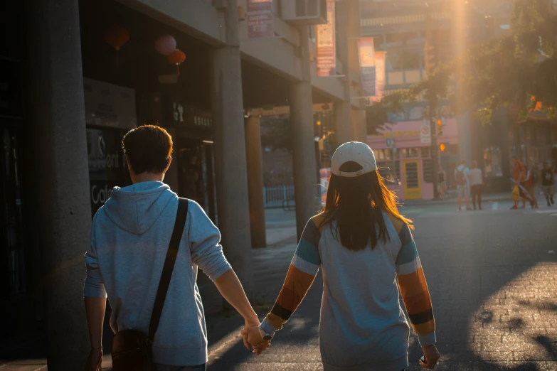 a young couple walking down the street with the sunlight shining