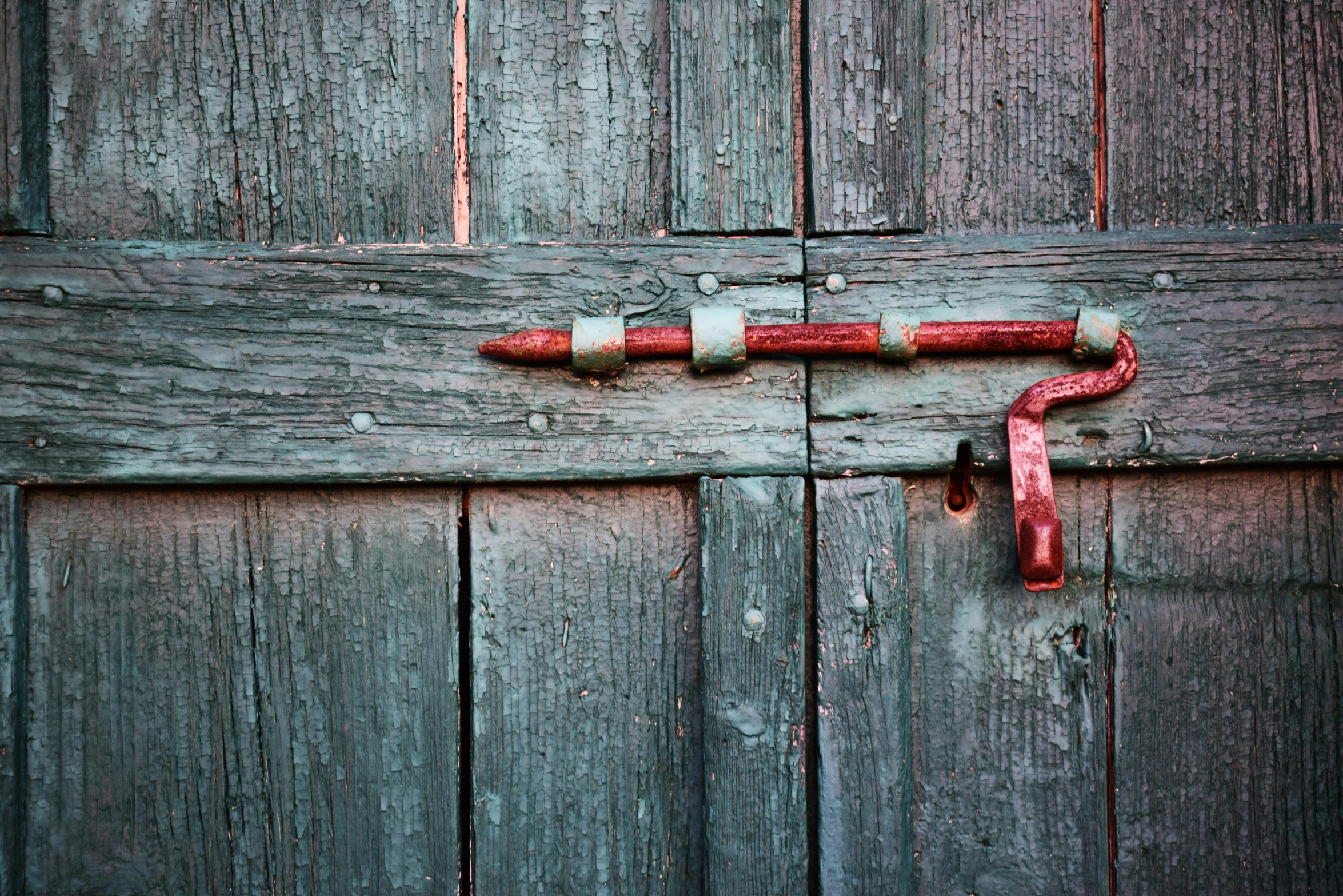 a handle on a wooden door painted teal and red