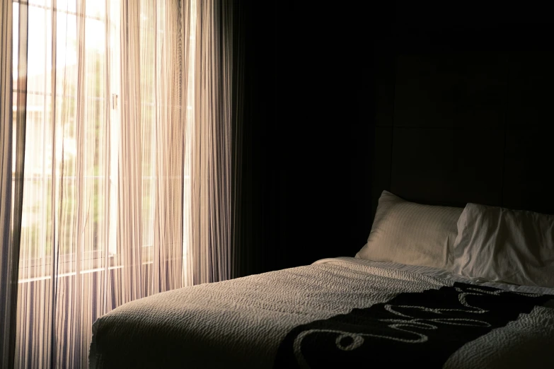 a very dark bedroom with a big window behind it