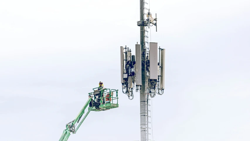 workers are repairing an antenna in the daytime