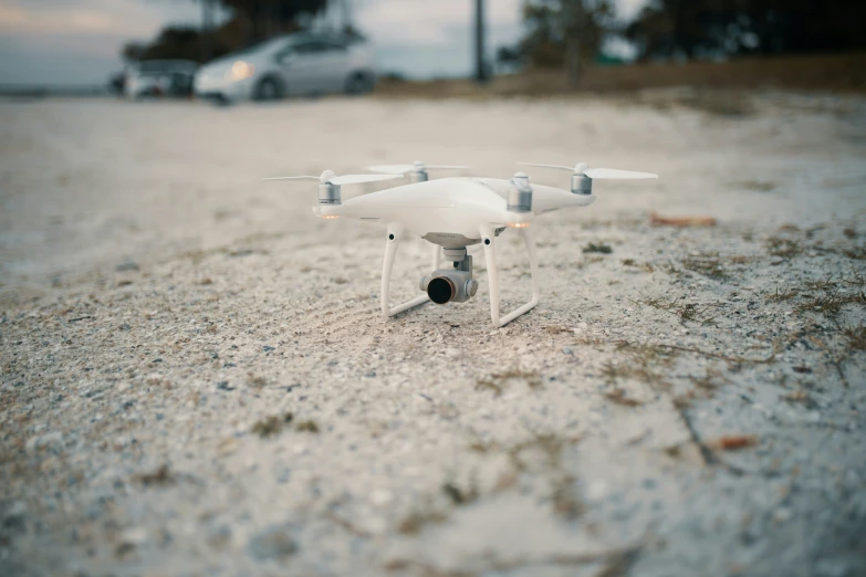 a small white remote controlled flying device sitting in the sand