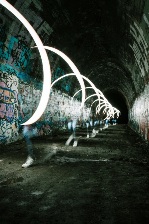 a tunnel with people walking down it has graffiti all over it