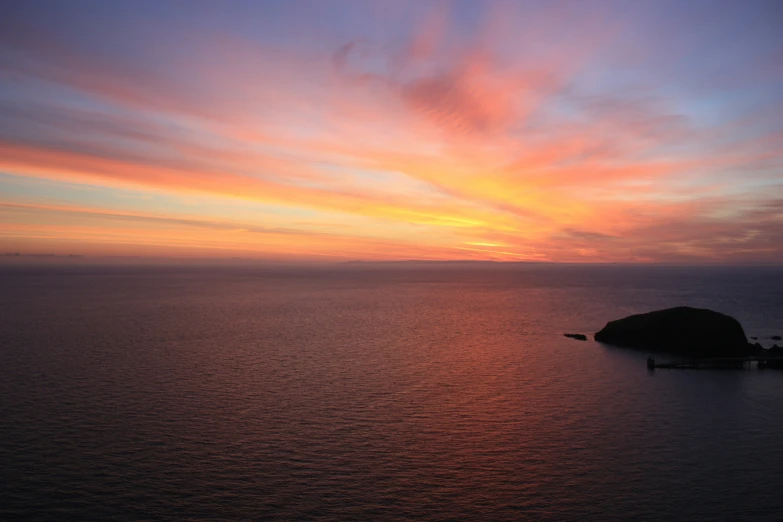 the sun is rising over a body of water