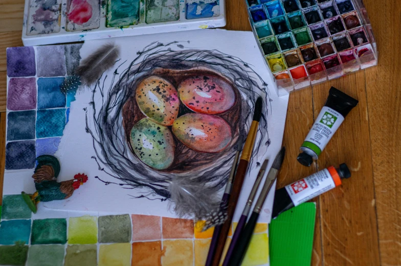 some watercolors a painting a bird nest and other paint supplies