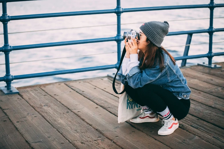 woman in hat crouching on wooden dock near water