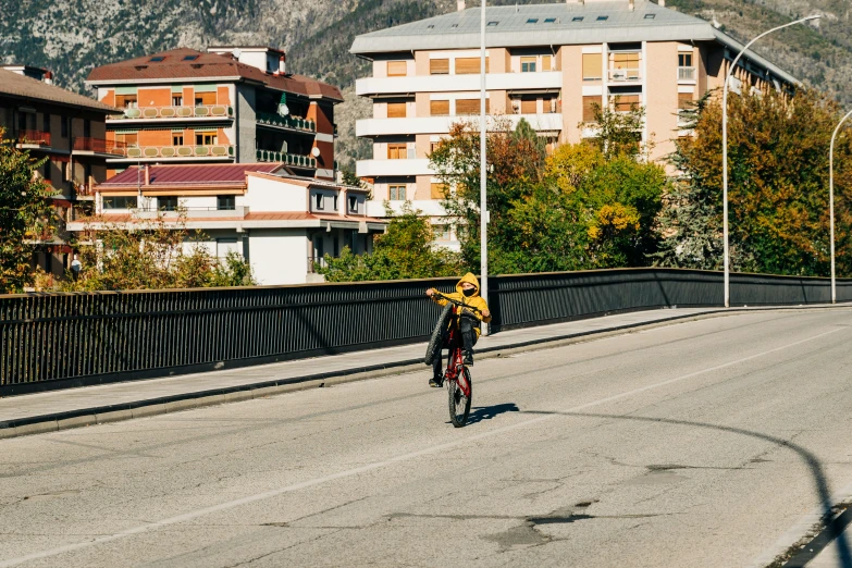 man on bicycle going over bridge toward city with buildings