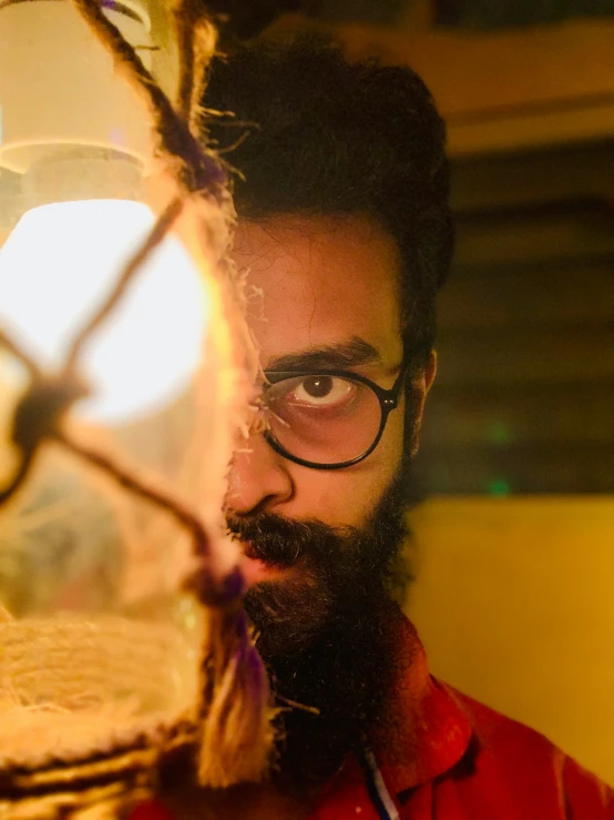 a man with eyeglasses looking through a wire fence