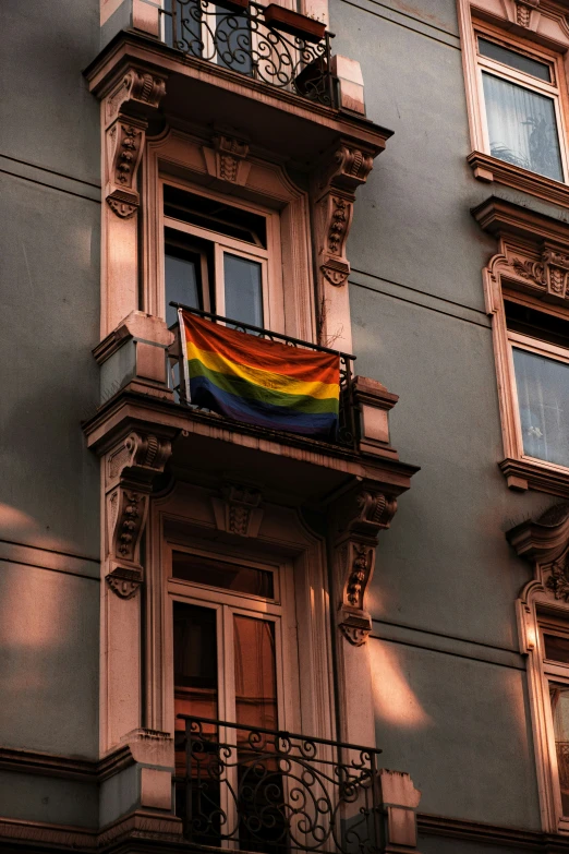 a large multi - colored flag hanging in a tall window