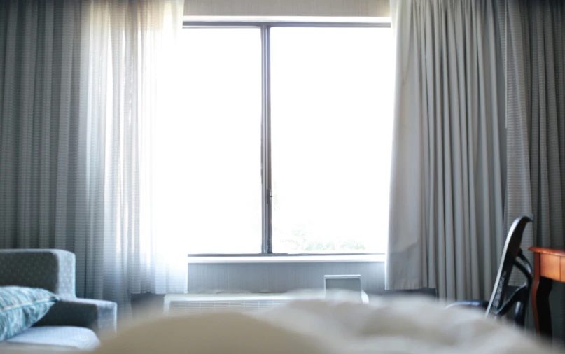 a view of a couch, chair and curtains from the inside of a room