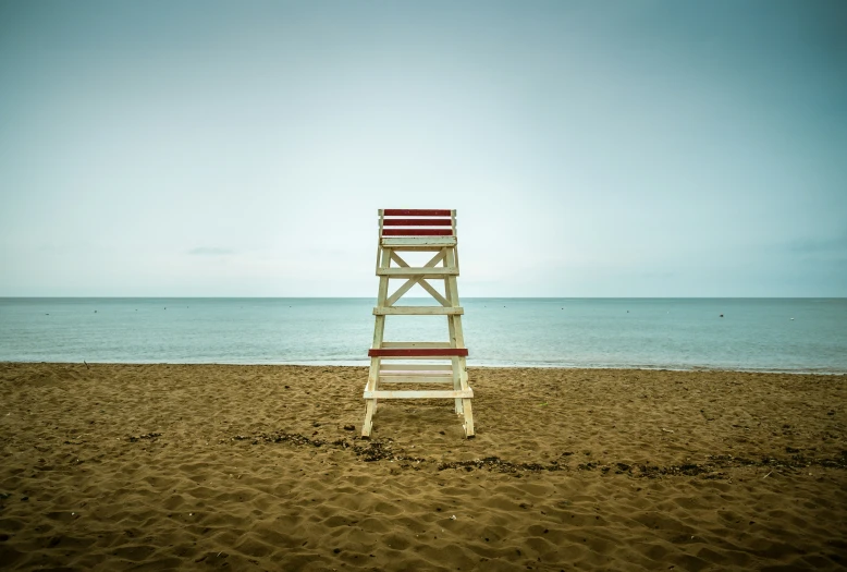 a wooden ladder sitting on top of a sandy beach