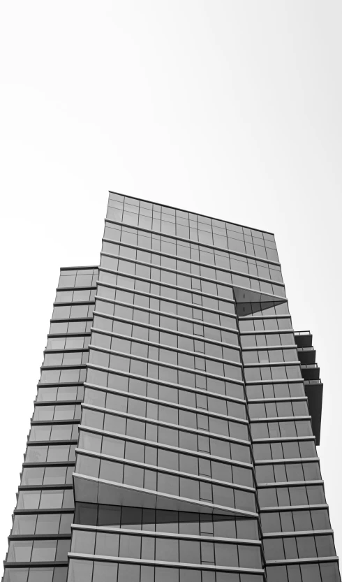 a large grey building with some windows and a plane flying in the sky