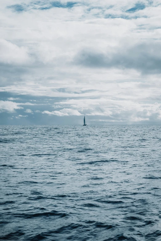 an outcast day looks over a sailboat out into the ocean