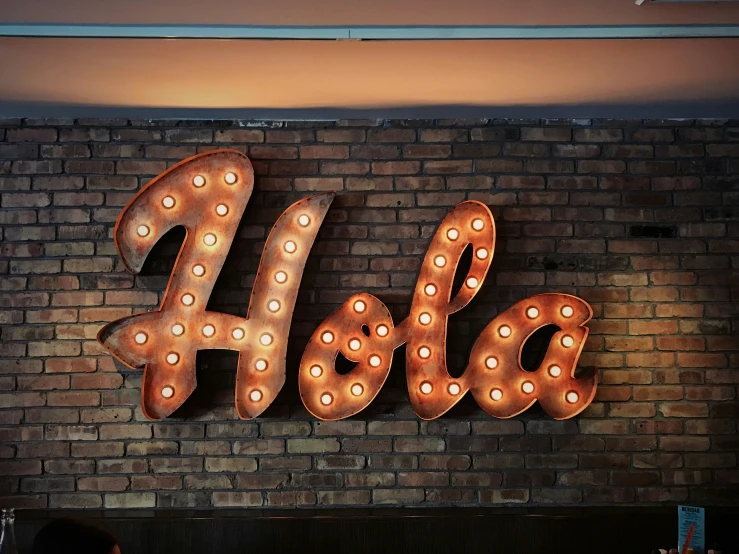 this sign shows the word holbe and lighted letters are attached to a brick wall