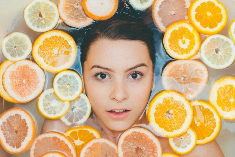 a person with fruit around their faces in water