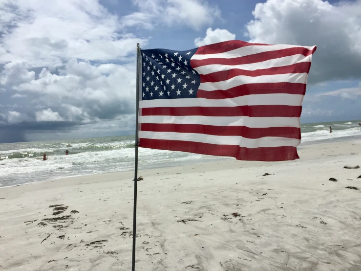 an american flag blowing in the wind near the beach