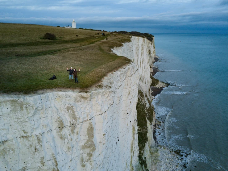 a group of people standing on top of a white cliff next to the ocean