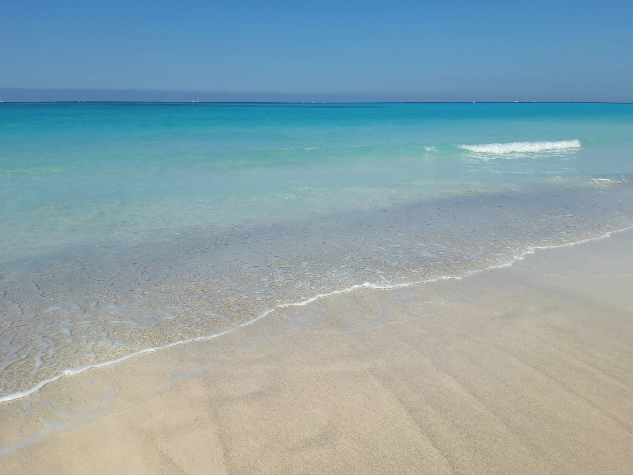 water and sand with two boats in the background