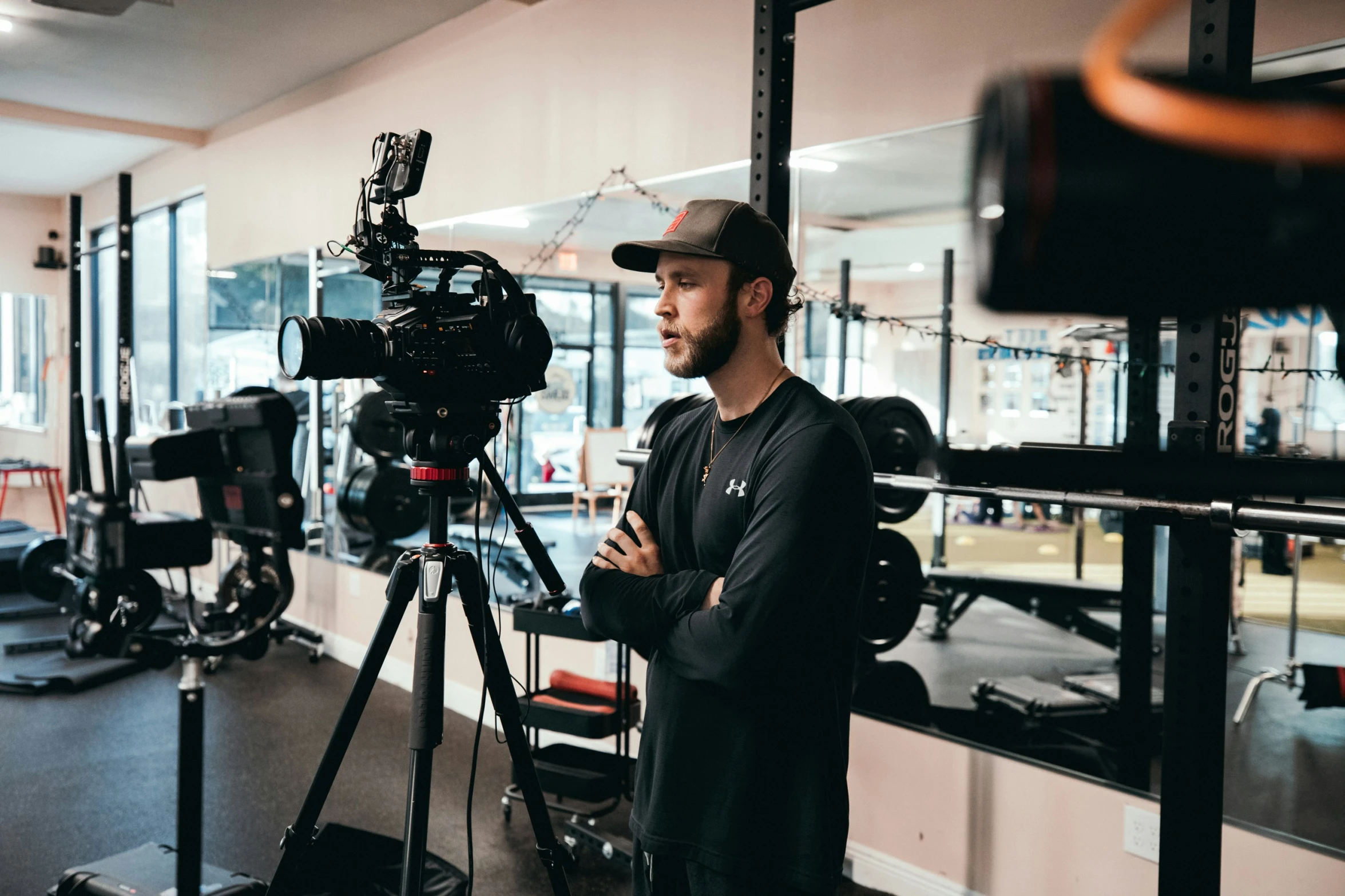 a man in black jacket and hat standing next to a camera