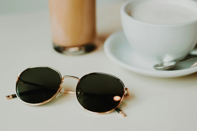 a cup of coffee next to a pair of sunglasses