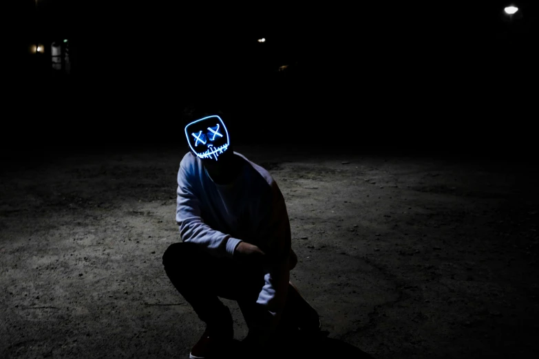 person sitting on skateboard wearing a blue mask in the dark