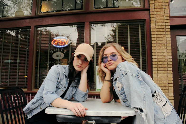 two girls are sitting together and talking on cell phones