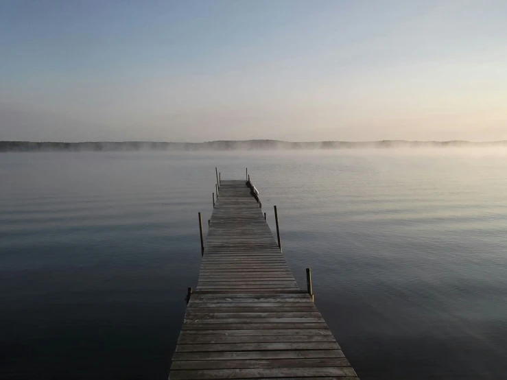 a long pier with fog floating on it