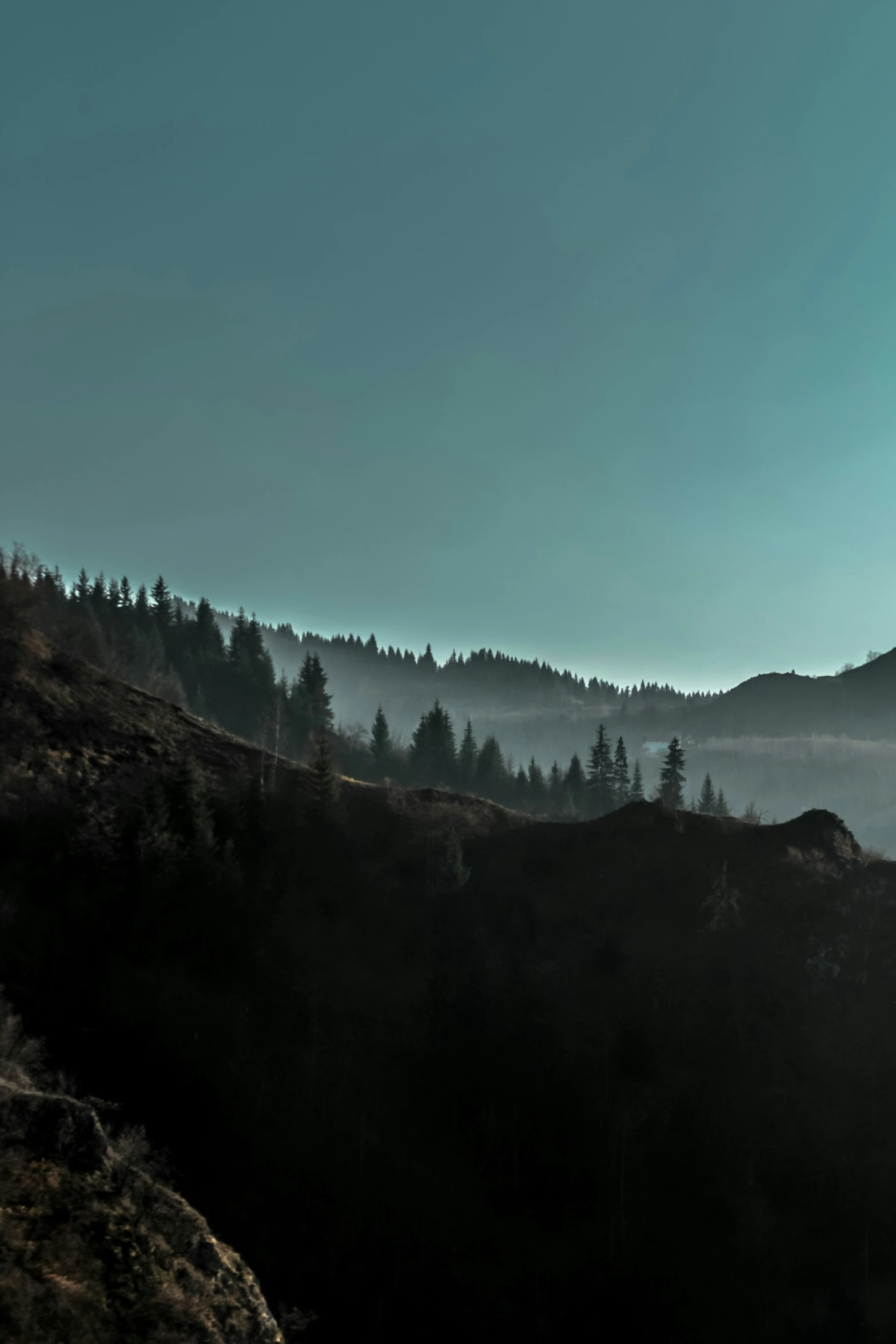 a view of mountains with mist and trees in the distance