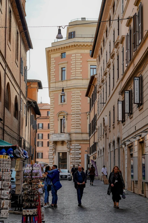 a group of people walking down a street with buildings on both sides