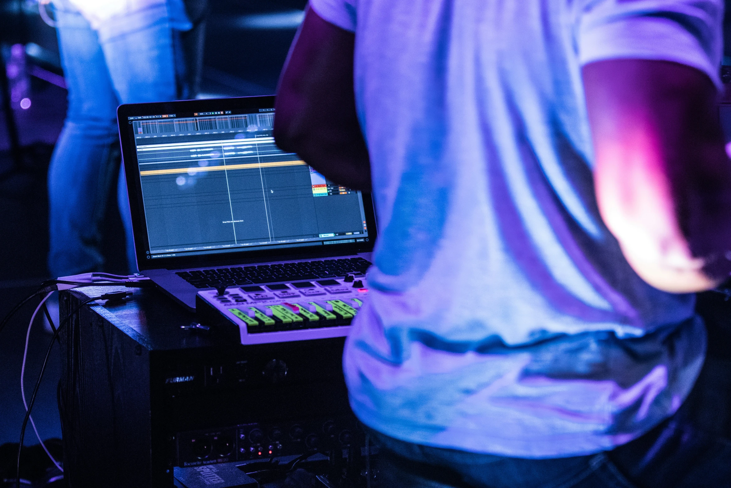 a person using his laptop next to a sound mixing console