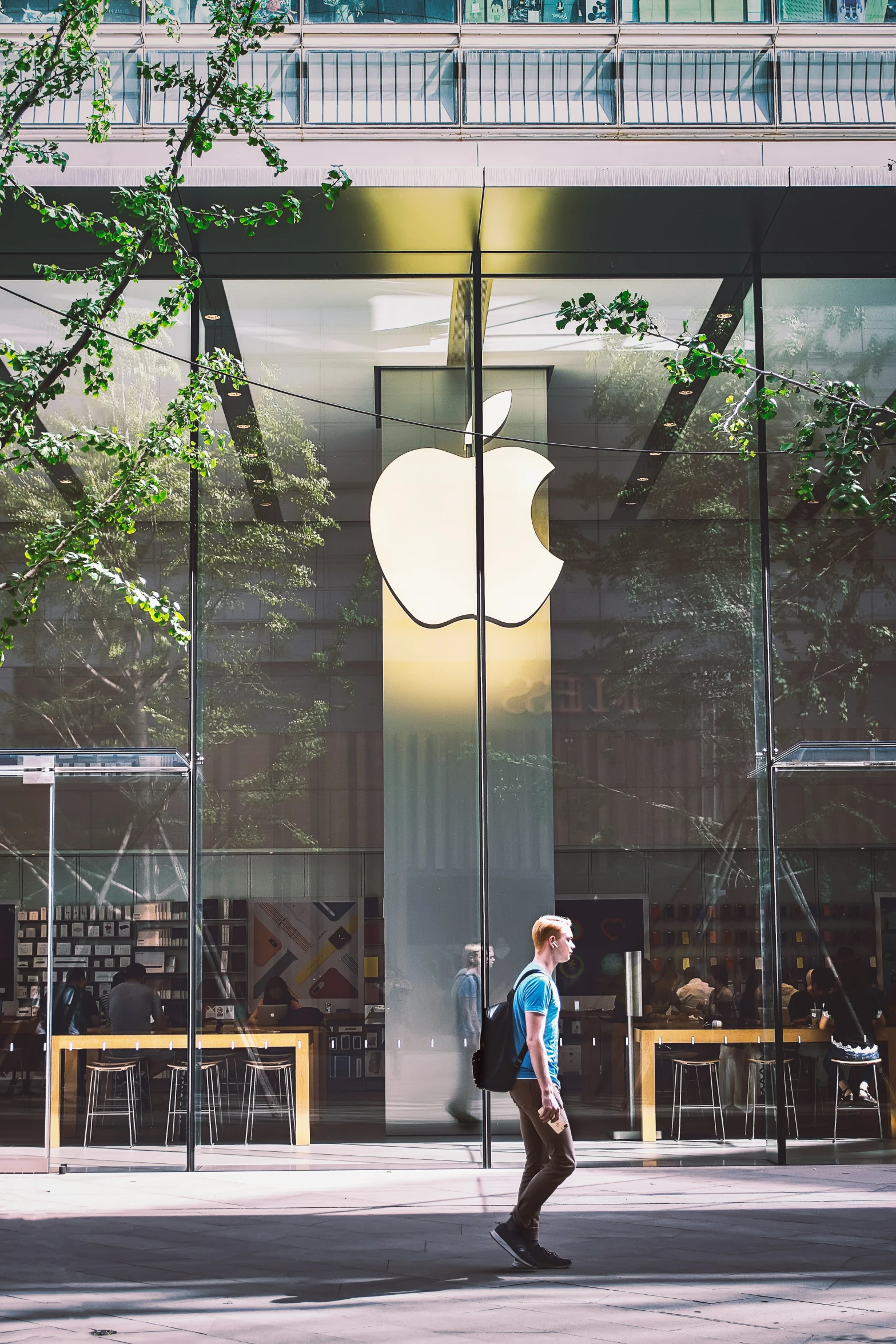 man walking down street in front of apple store