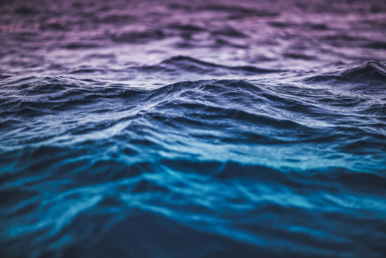 an ocean with dark purple, blue, and pink waves